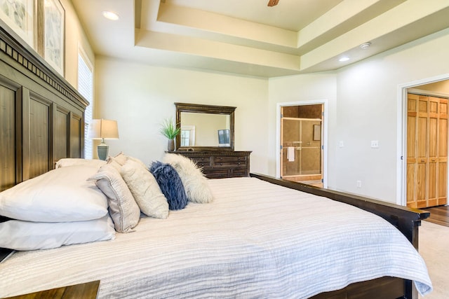 bedroom featuring a raised ceiling, wood-type flooring, and connected bathroom