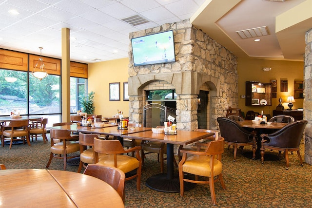 dining space featuring carpet flooring and a stone fireplace