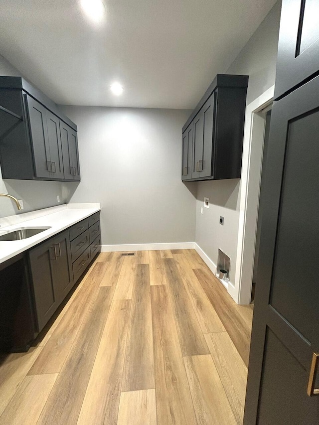 washroom with cabinets, light hardwood / wood-style floors, electric dryer hookup, and sink