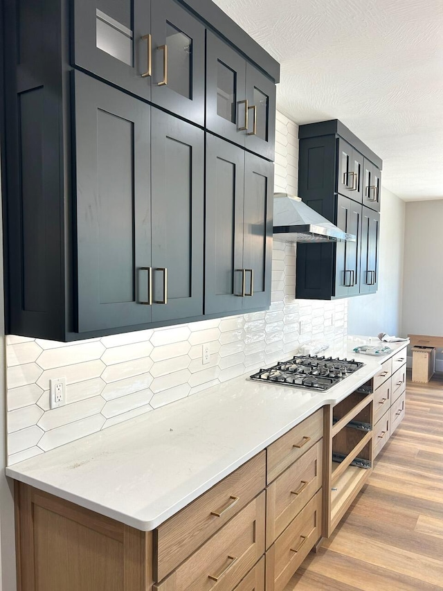 kitchen featuring light stone counters, light wood-type flooring, backsplash, and gas cooktop