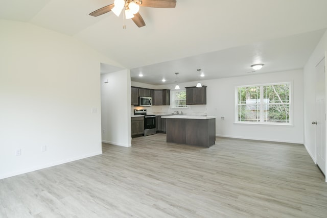 kitchen with lofted ceiling, hanging light fixtures, stainless steel appliances, a center island, and light hardwood / wood-style floors