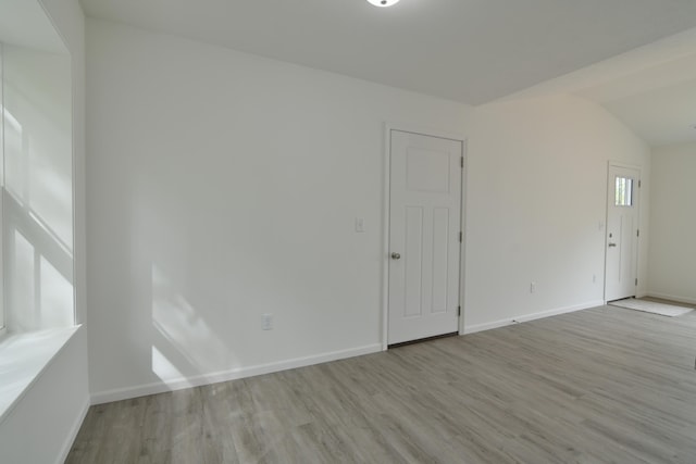 empty room featuring vaulted ceiling and light hardwood / wood-style flooring