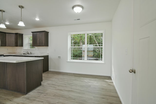 kitchen with dark brown cabinets, sink, hanging light fixtures, and light hardwood / wood-style floors