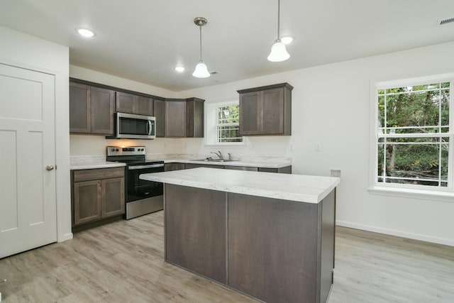 kitchen with appliances with stainless steel finishes, plenty of natural light, hanging light fixtures, and light hardwood / wood-style floors