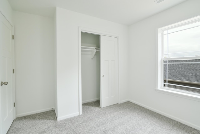 unfurnished bedroom with a closet and light colored carpet