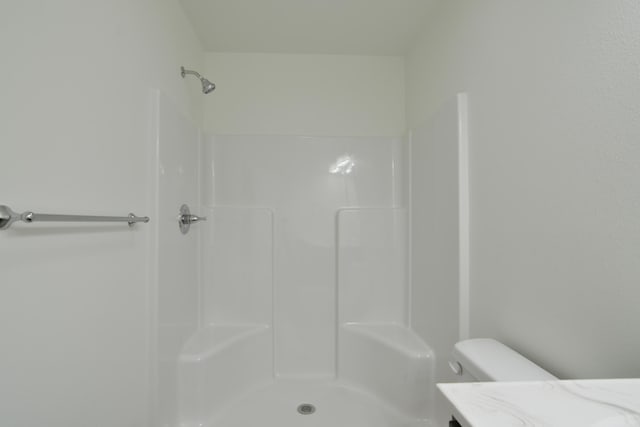 bathroom featuring toilet, vanity, and a shower