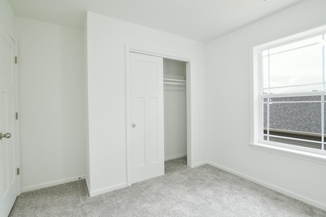 unfurnished bedroom with a closet and light colored carpet