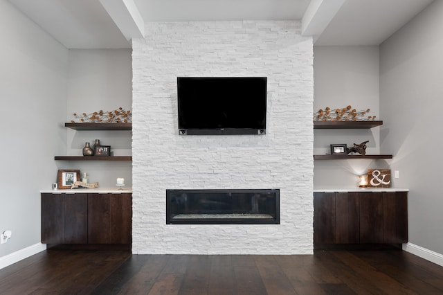 unfurnished living room featuring dark hardwood / wood-style flooring and a stone fireplace