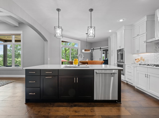 kitchen with appliances with stainless steel finishes, sink, an island with sink, and white cabinets