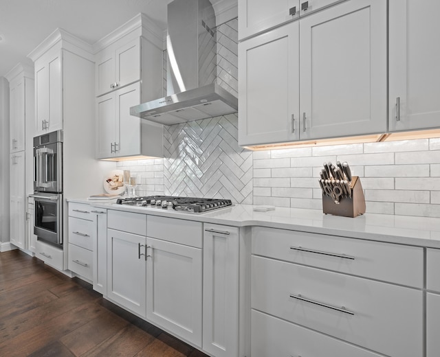 kitchen featuring dark hardwood / wood-style floors, wall chimney range hood, stainless steel appliances, and white cabinets