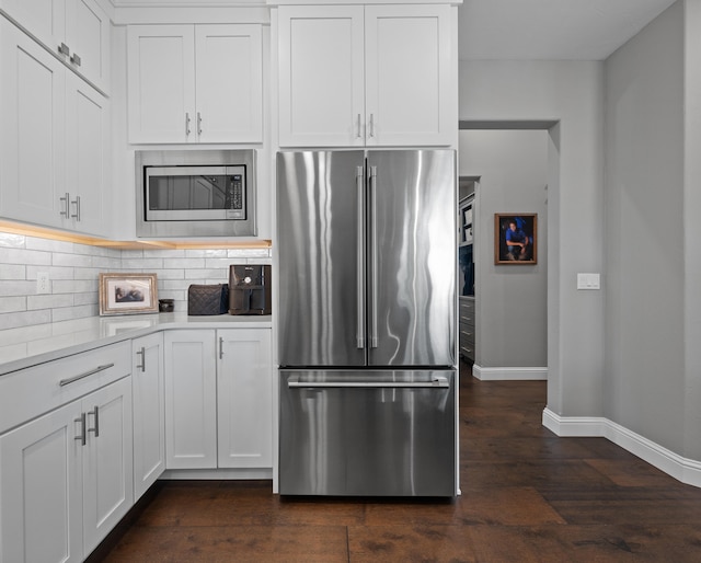 kitchen featuring stainless steel appliances, backsplash, dark wood-type flooring, and white cabinetry