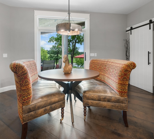 dining area with a barn door and dark hardwood / wood-style flooring