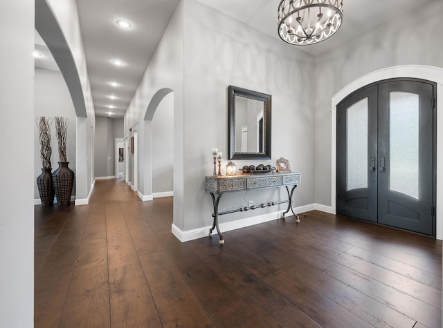 foyer entrance with french doors, an inviting chandelier, and dark hardwood / wood-style flooring