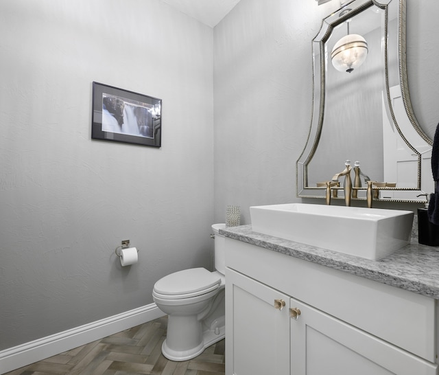 bathroom featuring vanity, toilet, and parquet floors