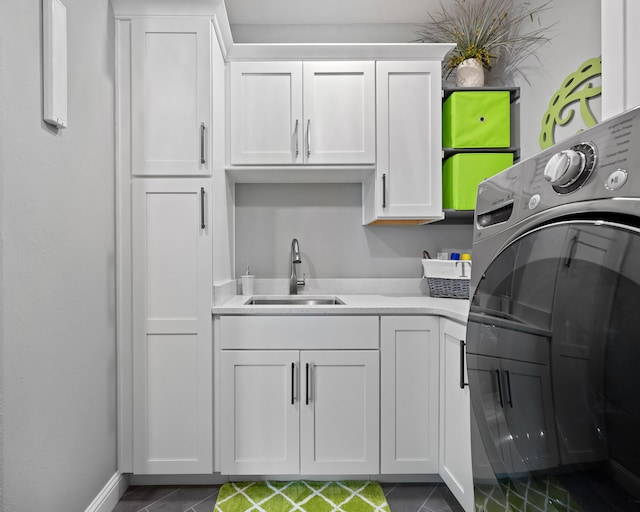 laundry area with dark tile patterned floors, washer / dryer, sink, and cabinets