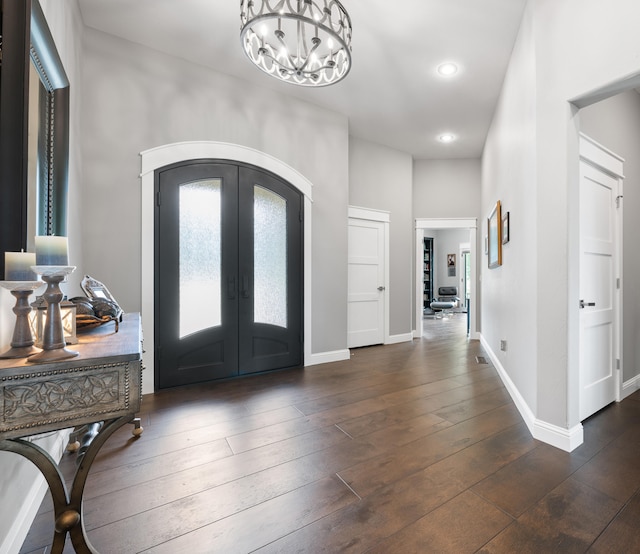 foyer with french doors, a notable chandelier, and dark hardwood / wood-style flooring