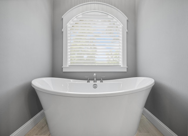 bathroom with hardwood / wood-style flooring and a tub to relax in