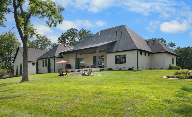 back of property with a fire pit, a lawn, and a patio area