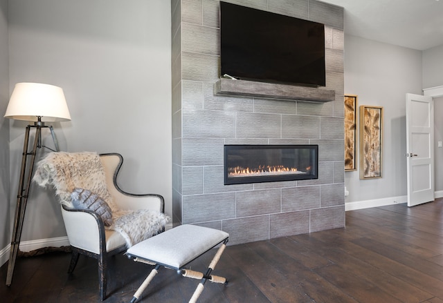 sitting room featuring a tile fireplace and dark hardwood / wood-style floors