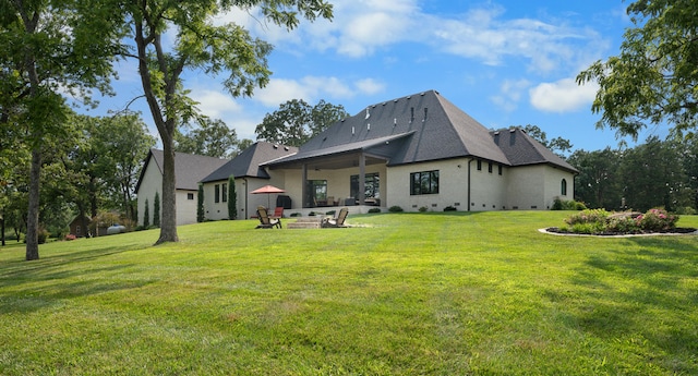 back of property with a yard, a patio, and an outdoor fire pit