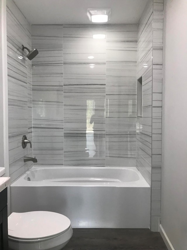 full bathroom with wood-type flooring, vanity, tiled shower / bath combo, and toilet