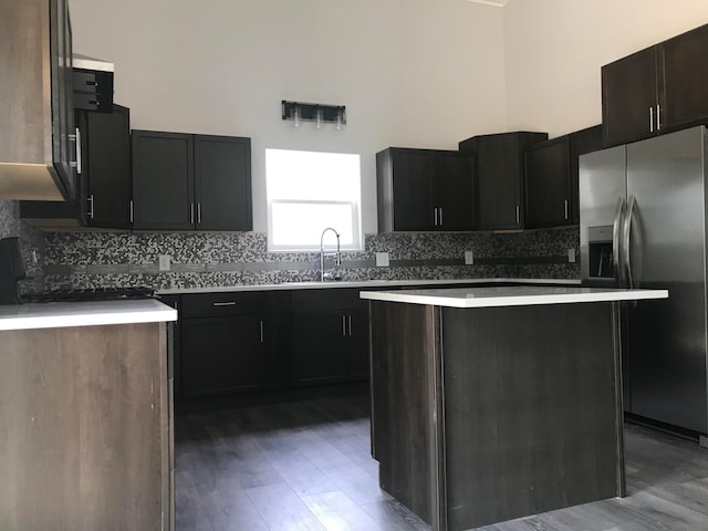 kitchen with sink, tasteful backsplash, a kitchen island, wood-type flooring, and stainless steel refrigerator with ice dispenser