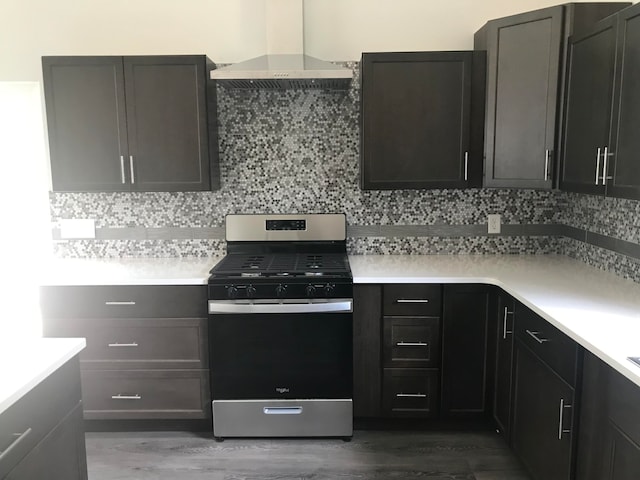 kitchen with stainless steel range with gas cooktop, wall chimney range hood, decorative backsplash, and hardwood / wood-style floors