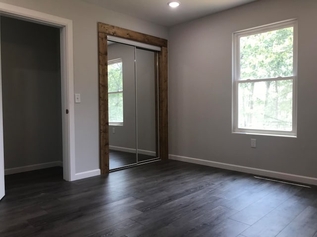 unfurnished bedroom with a closet and dark hardwood / wood-style flooring