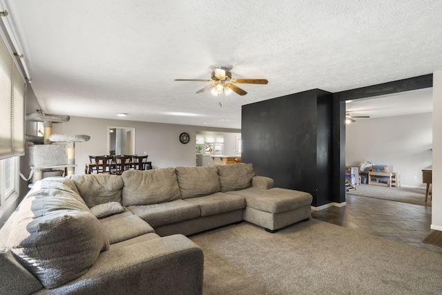 carpeted living room with ceiling fan, a textured ceiling, and plenty of natural light