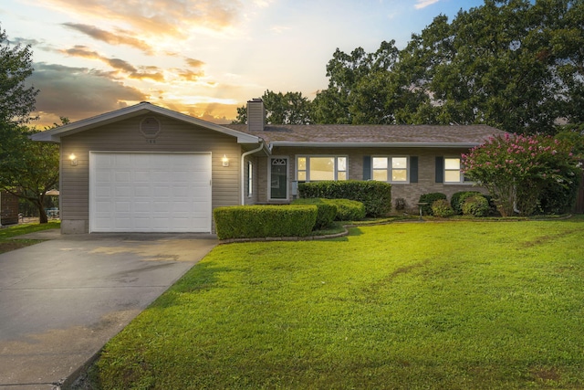 ranch-style home featuring a garage and a yard