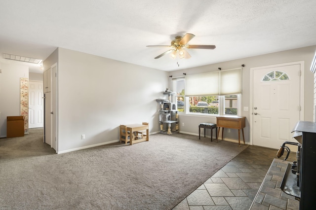 entrance foyer with ceiling fan, dark carpet, and a textured ceiling