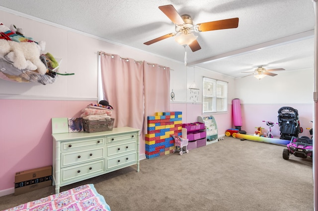 rec room with ceiling fan, dark carpet, ornamental molding, and a textured ceiling