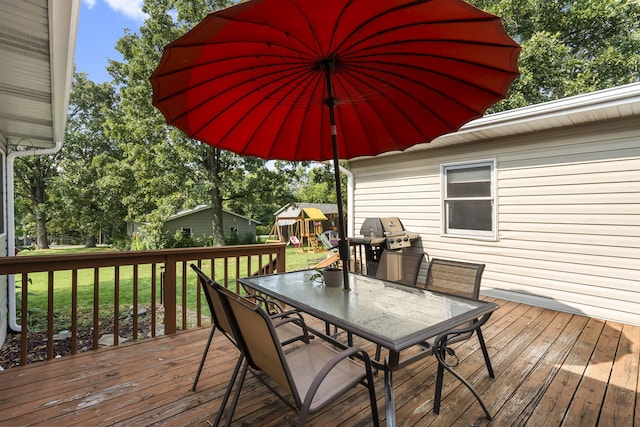 wooden deck with a playground, a grill, and a lawn