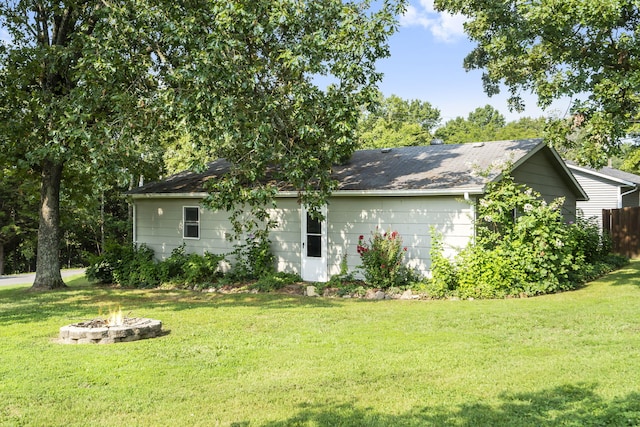 rear view of house featuring an outdoor fire pit and a yard