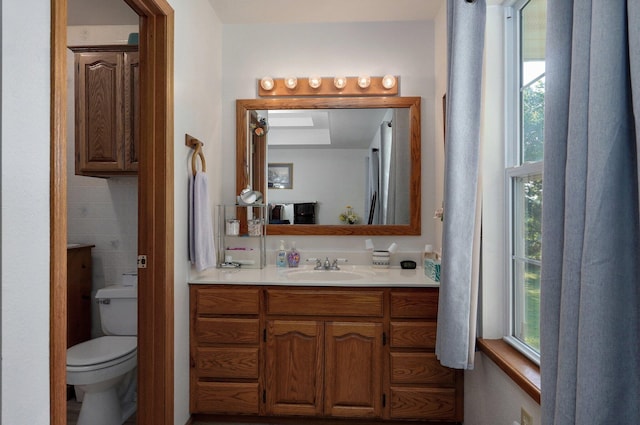 bathroom featuring tile walls, vanity, and toilet