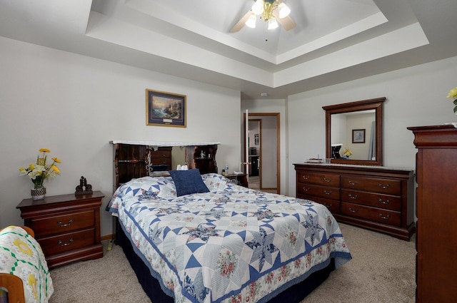 bedroom with ceiling fan, light colored carpet, and a raised ceiling