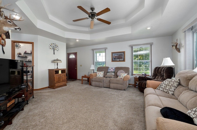 living room with light carpet, ceiling fan, and a raised ceiling