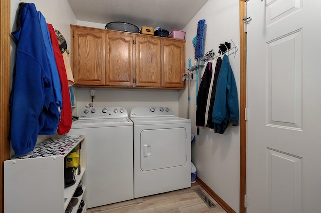 washroom featuring light hardwood / wood-style floors, cabinets, and washer and clothes dryer