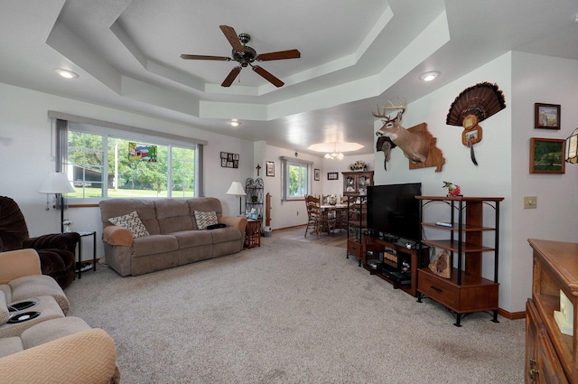 living room with a wealth of natural light, a tray ceiling, and light colored carpet