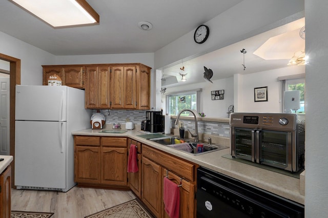 kitchen featuring black dishwasher, plenty of natural light, sink, and white fridge