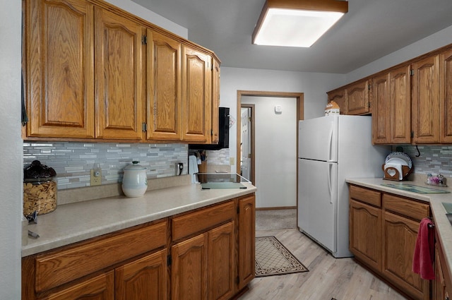 kitchen with decorative backsplash, light hardwood / wood-style floors, and white fridge