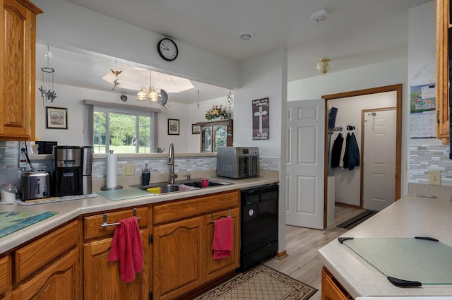 kitchen featuring light hardwood / wood-style flooring, black dishwasher, sink, and backsplash