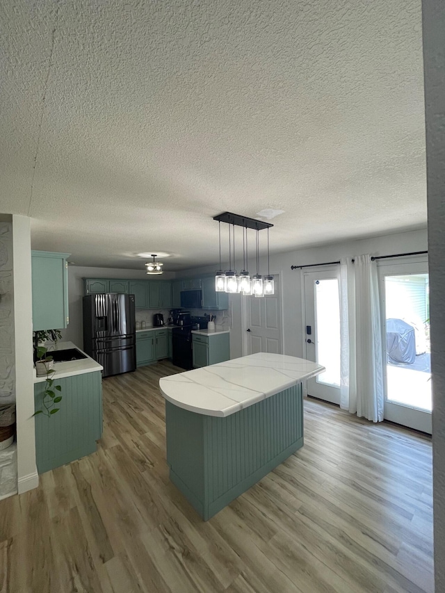 kitchen featuring decorative light fixtures, stainless steel fridge with ice dispenser, black electric range oven, and light wood-type flooring