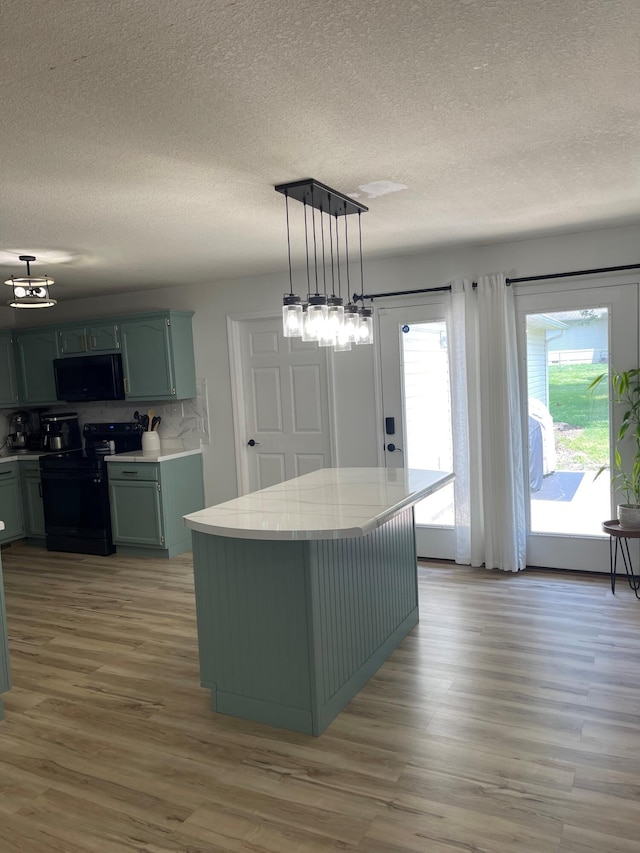 kitchen featuring pendant lighting, tasteful backsplash, black appliances, green cabinets, and hardwood / wood-style floors