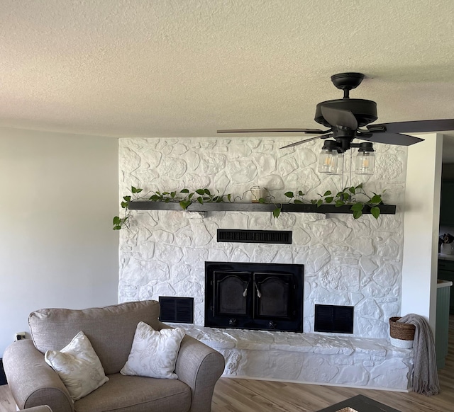 unfurnished living room featuring hardwood / wood-style flooring, a fireplace, ceiling fan, and a textured ceiling