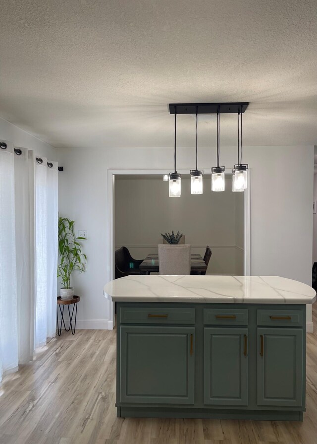 kitchen featuring light stone counters, pendant lighting, a textured ceiling, and light hardwood / wood-style flooring