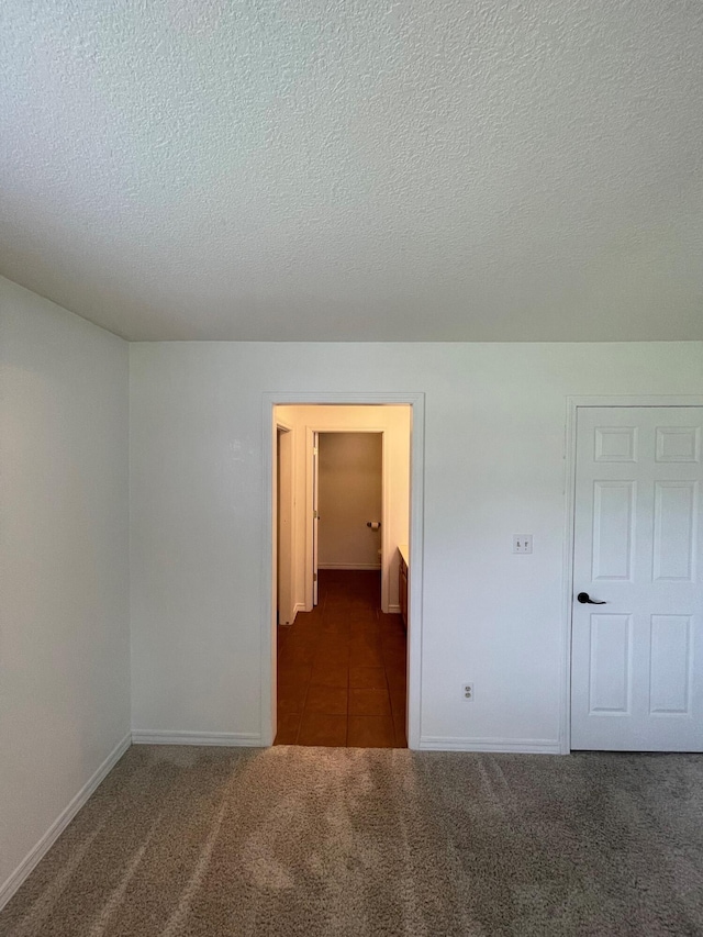 unfurnished room featuring dark colored carpet and a textured ceiling