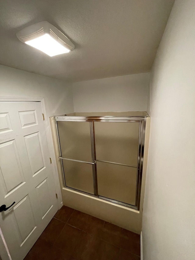 bathroom with a textured ceiling, tile patterned flooring, and a shower with door