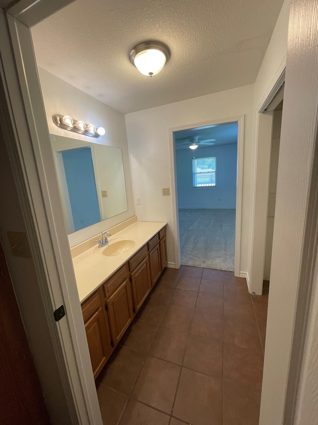 bathroom featuring tile patterned flooring, ceiling fan, vanity, and a textured ceiling