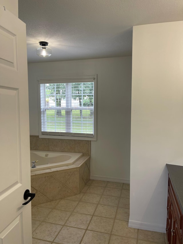 bathroom featuring a relaxing tiled tub, vanity, a textured ceiling, and tile patterned floors